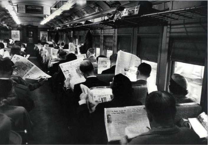 People reading a newspaper on a train