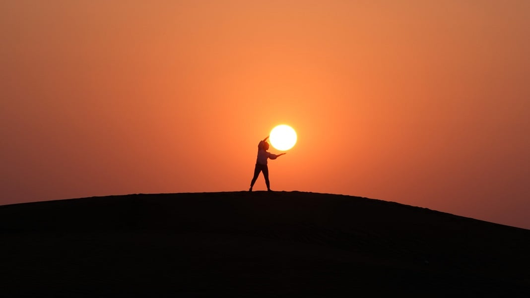 silhouette of a person appearing to hold the sun
