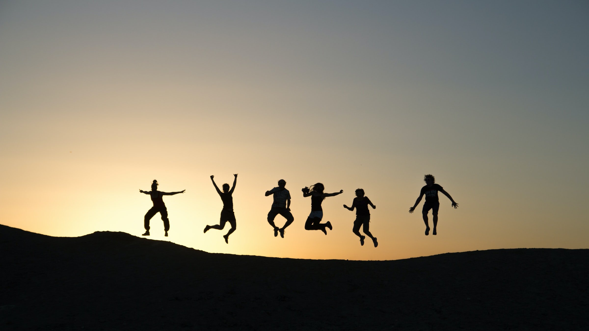 silhouette image of six people jumping in the air